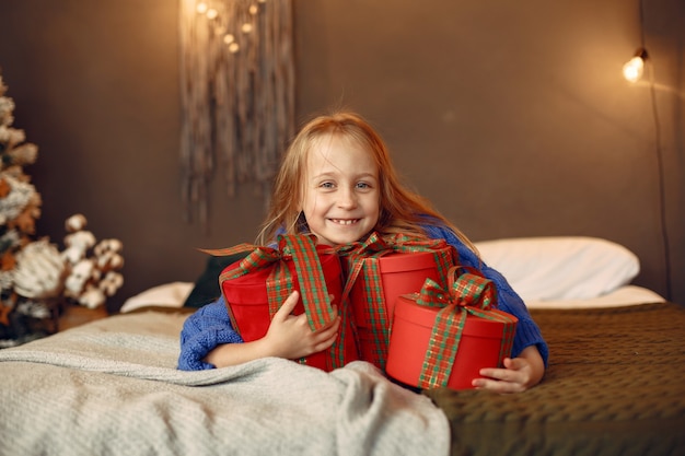 Bambino in un maglione blu. Figlia che si siede vicino all'albero di Natale.