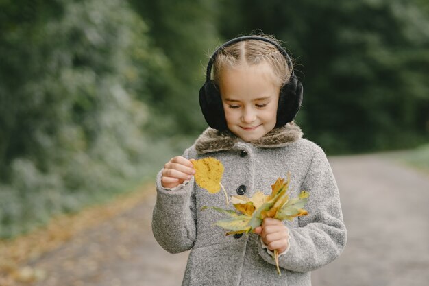 Bambino in un parco d'autunno. Ragazzo con un cappotto grigio.