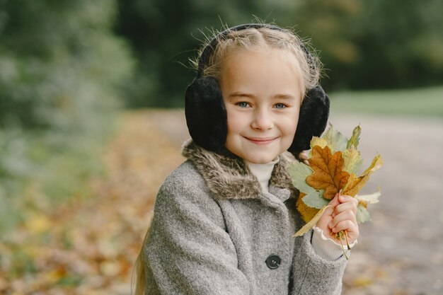 Bambino in un parco d'autunno. Ragazzo con un cappotto grigio.