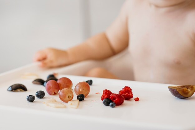 Bambino nel seggiolone scegliendo quale frutta mangiare close-up