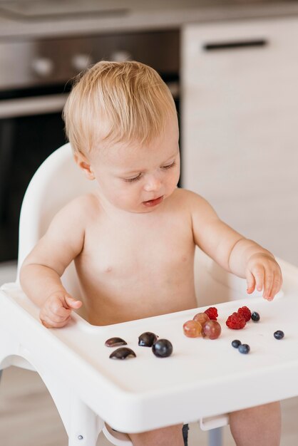 Bambino nel seggiolone scegliendo quale frutta mangiare