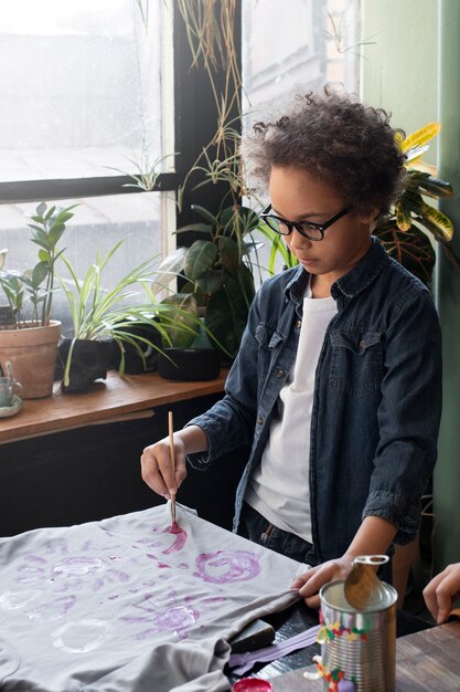 Bambino piccolo che fa un progetto di artigianato fai-da-te con t-shirt