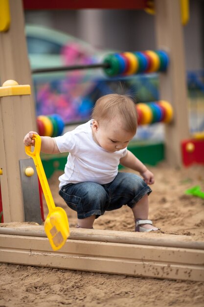 Bambino serio bambino che gioca nel parco giochi sandbox