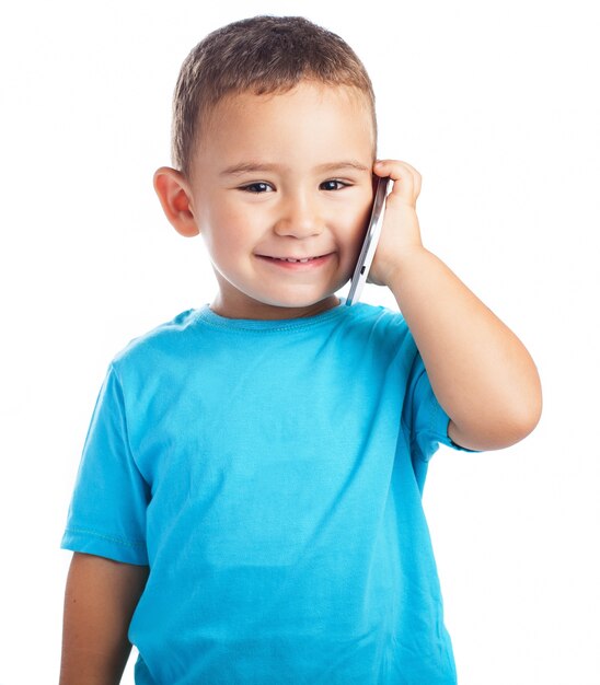 Bambino sorridente con un telefono in un orecchio