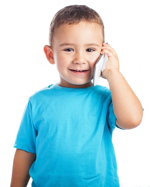 Bambino sorridente con un telefono in un orecchio