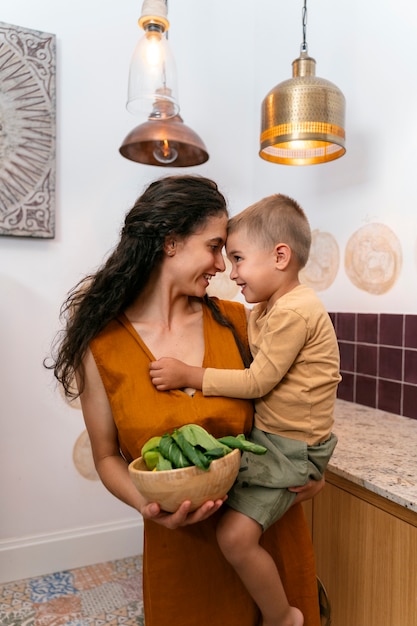 Bambino sorridente della holding della madre di vista frontale