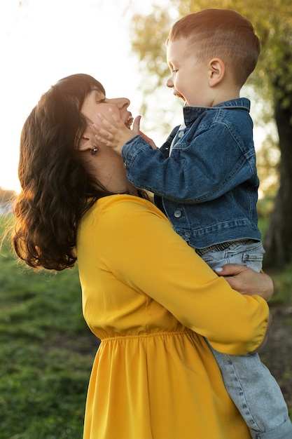 Bambino sorridente della holding della madre di vista laterale