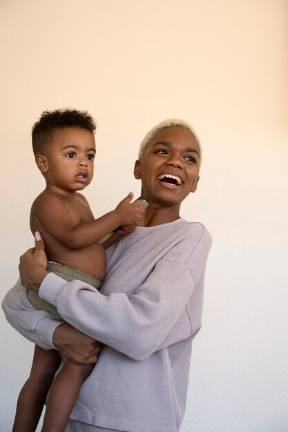 Bambino sorridente della holding della madre di vista laterale