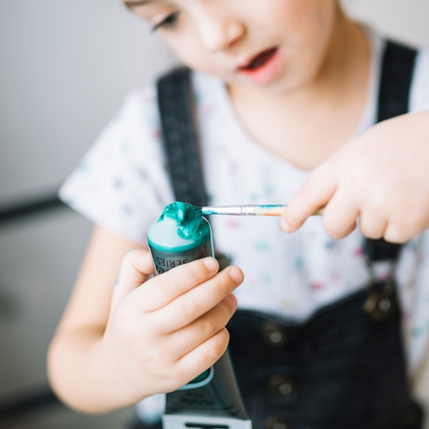 Bambino stupito con tubo di colori e pennello nelle mani