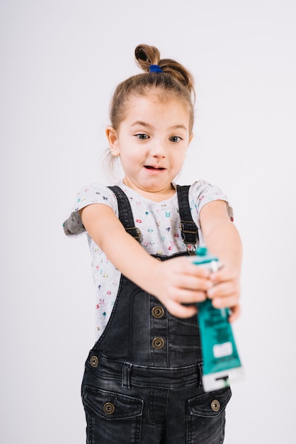 Bambino stupito con tubo di colori nelle mani