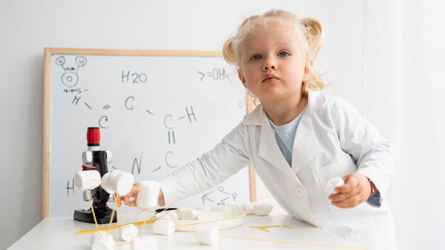 Bambino sveglio che impara sulla scienza con la lavagna e il microscopio