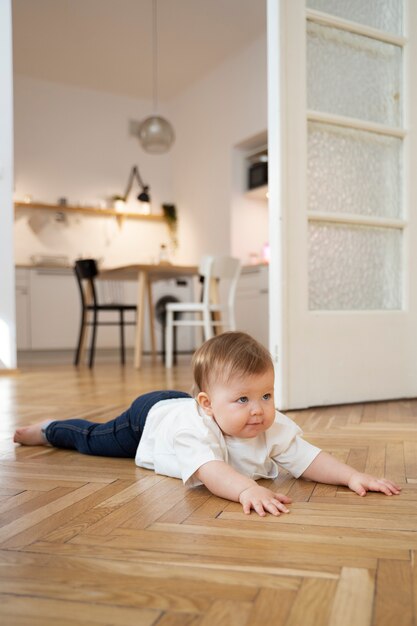 Bambino sveglio del colpo pieno che posa sul pavimento