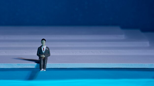 Bambola uomo seduto accanto alla piscina con copia spazio