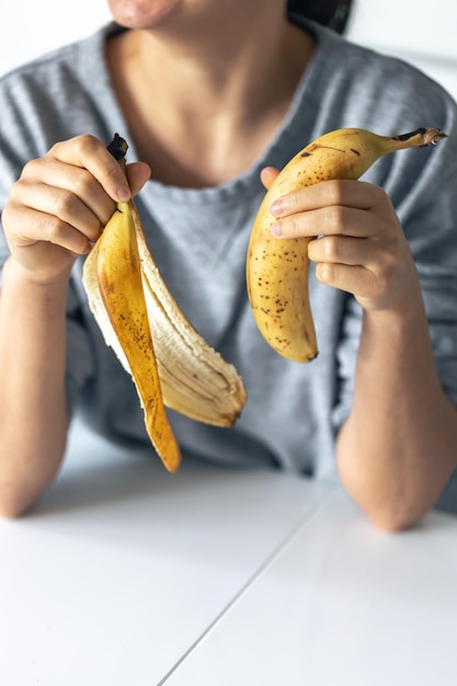 Banana e buccia di banana in primo piano delle mani femminili