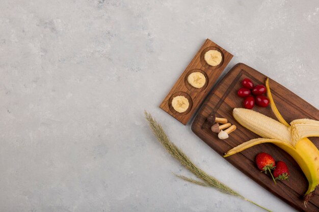 Banana, fragola e frutti di bosco su un piatto di legno