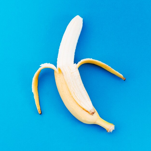 Banana ripulito dalla buccia su una superficie luminosa