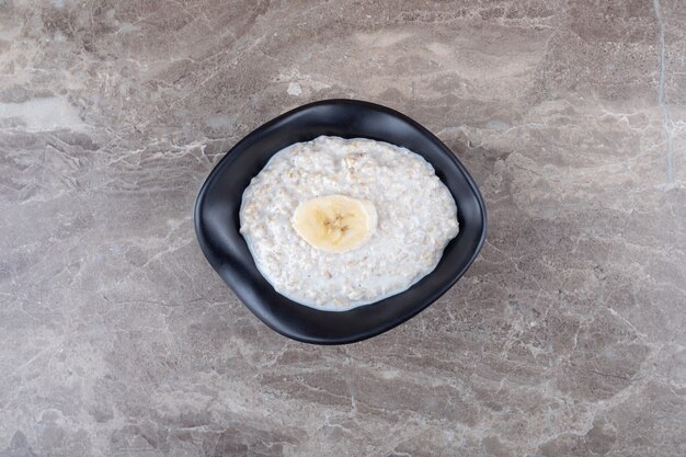 Banane a fette mature su una ciotola di porridge, sulla superficie di marmo