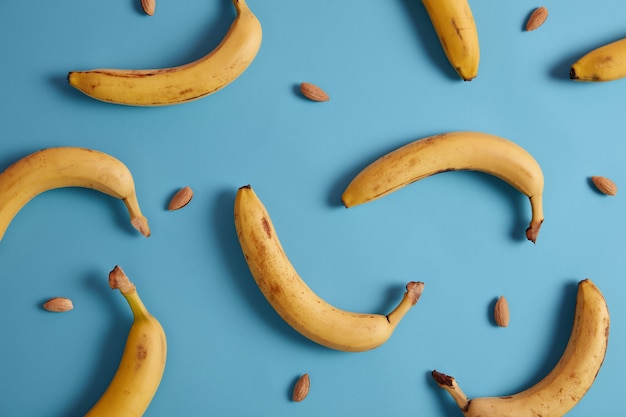 Banane e mandorle su sfondo blu. Selezione di cibi sani per il cuore. Fonte di vitamine, fibre alimentari e minerali. Alimentazione sana e prodotti per dimagrire. Ingredienti per la colazione