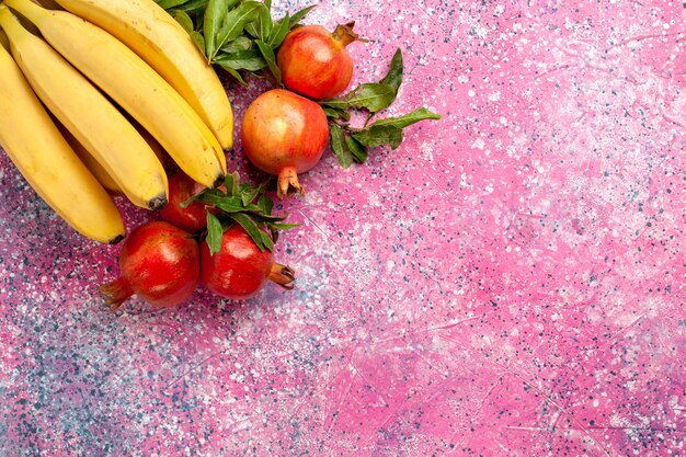 Banane gialle vista dall'alto con melograni sulla superficie rosa