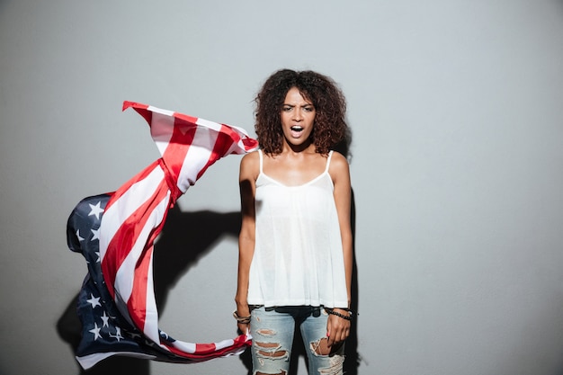 Bandiera americana e gridare della giovane donna afroamericana della tenuta