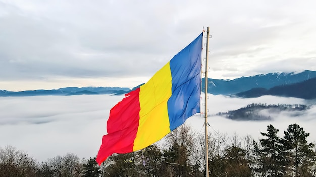 Bandiera nazionale sulla cima di una collina vicino a Barsov alberi spogli nuvole basse Romania