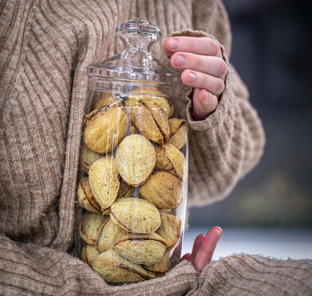 Barattolo di vetro con noci di biscotti con latte condensato in mani femminili