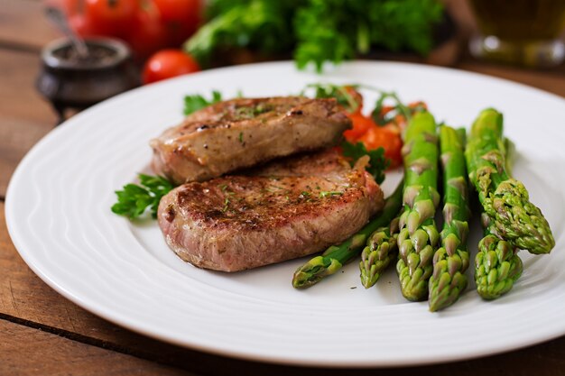 Barbecue bistecca di manzo alla griglia con asparagi e pomodori.