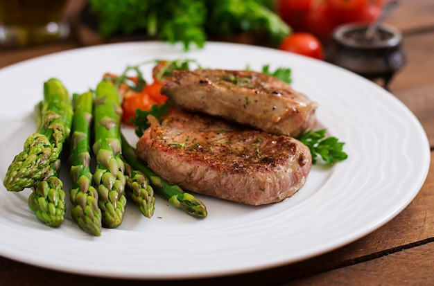 Barbecue bistecca di manzo alla griglia con asparagi e pomodori.