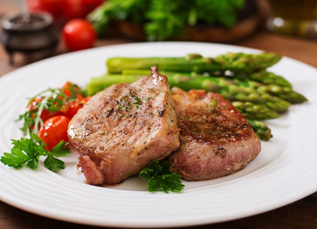 Barbecue bistecca di manzo alla griglia con asparagi e pomodori.