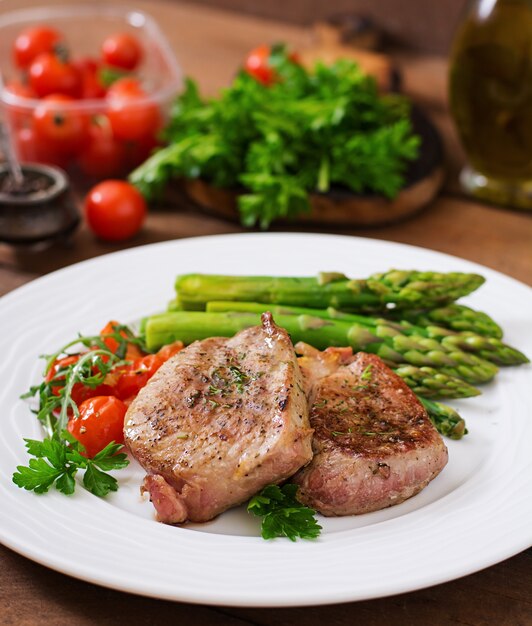 Barbecue bistecca di manzo alla griglia con asparagi e pomodori.