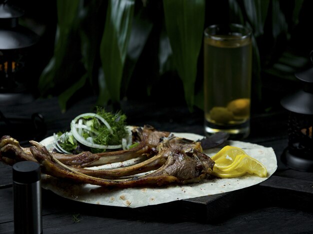 Barbecue di agnello servito in lavaash con erbe fresche e fettine di limone