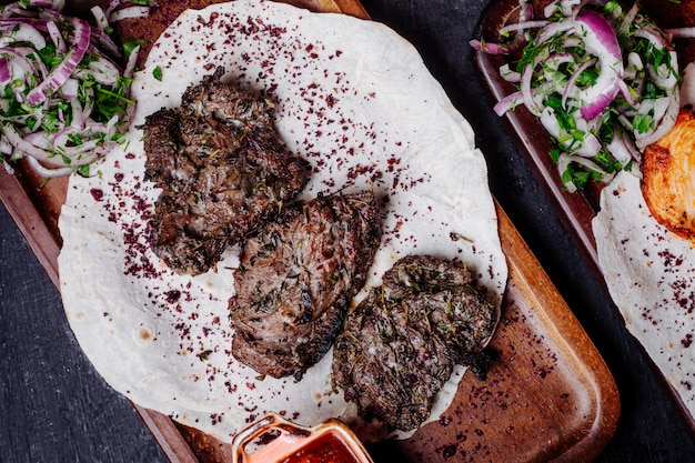 Barbecue di carne in lavash con involtini di cipolla e sumakh.