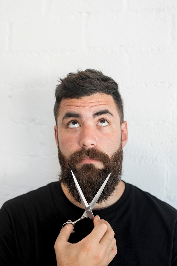 Foto gratuito barbiere che tiene le forbici professionali vicino alla barba al barbiere