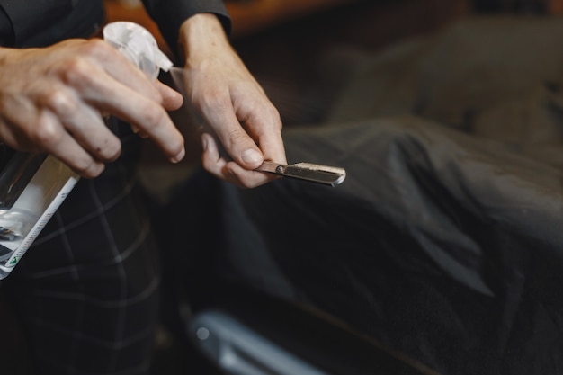 Barbiere. Il primo piano del barbiere tiene il rasoio per radersi la barba