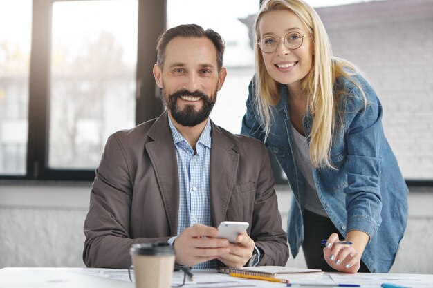 Barbuto manager maschio in abito formale e la sua assistente femminile