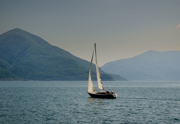 Barca a vela in mezzo al mare calmo sulle colline catturate in Svizzera