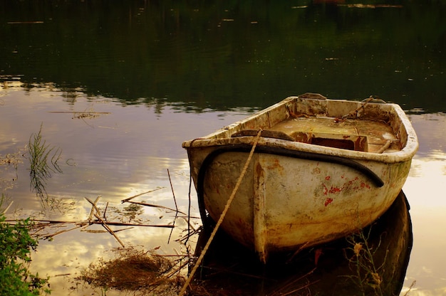Barca abbandonata arrugginita e vecchia stagionata sul lago nel parco