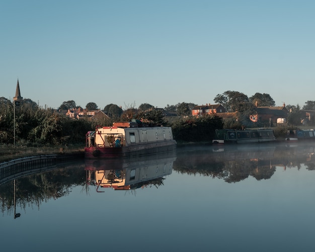 Barca in acqua vicino alla riva con edifici in lontananza sotto un cielo blu