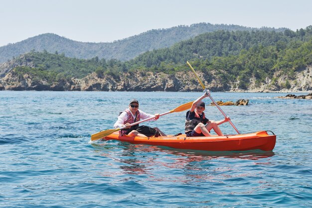 Barca in kayak vicino a scogliere in una giornata di sole. Kayak in una baia tranquilla. Viste incredibili. Viaggi, concetto di sport. Stile di vita. Una famiglia felice.