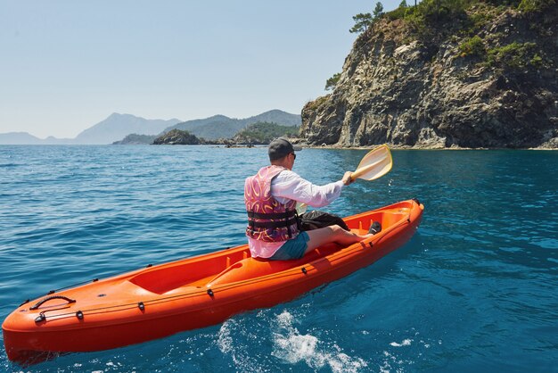 Barca in kayak vicino a scogliere in una giornata di sole. Viaggi, concetto di sport. Stile di vita.