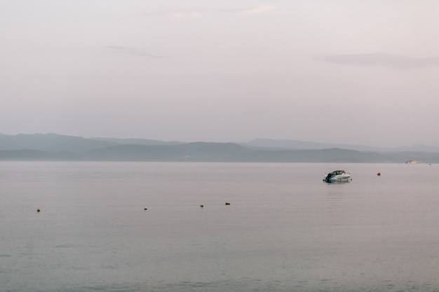 Barca solitaria galleggia nel mare sotto il cielo grigio