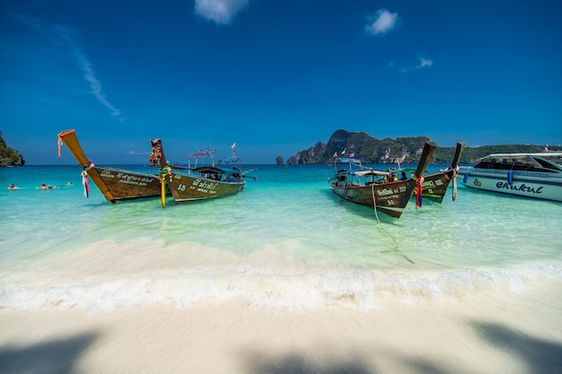 Barche a coda lunga che parcheggiano al bianco e alla spiaggia sull'isola di phi di Phi in Tailandia