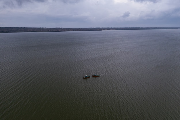 Barche da pesca, che galleggiano nelle acque calme e che vanno a pescare sotto un cielo di nuvole