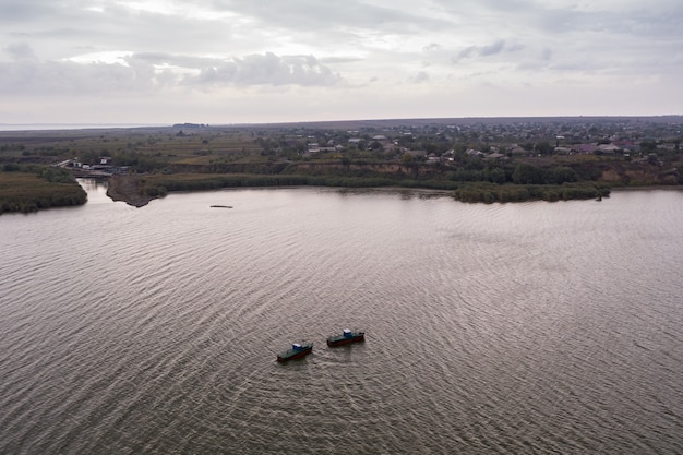 Barche da pesca, che galleggiano nelle acque calme e che vanno a pescare sotto un cielo di nuvole