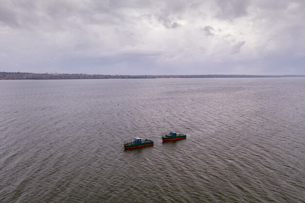 Barche da pesca, che galleggiano nelle acque calme e che vanno a pescare sotto un cielo di nuvole