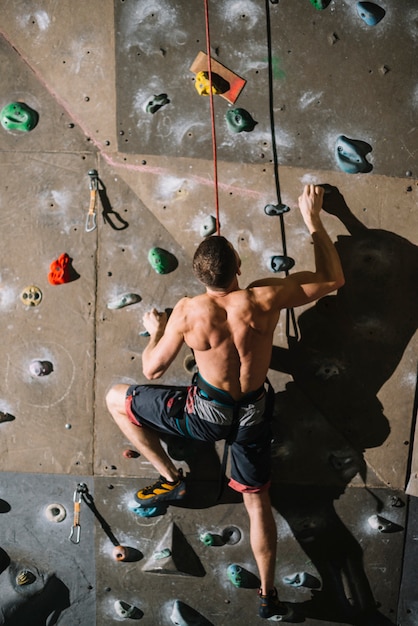 Barechested man climbing wall