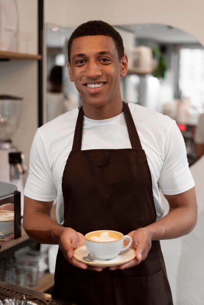 Barista a colpo medio che tiene in mano una tazza di caffè