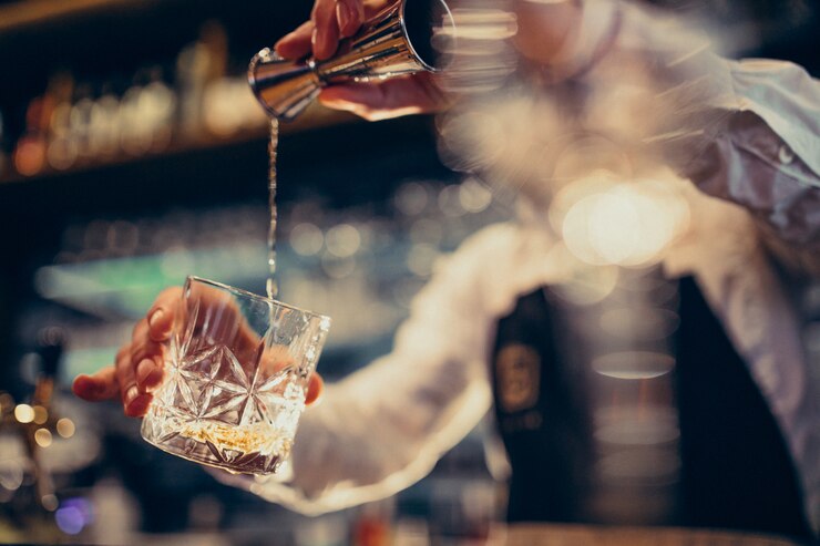 Foto gratuito barista bello che fa bere e cocktail ad un contatore