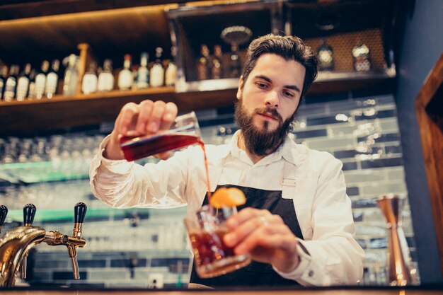 Barista bello che fa bere e cocktail ad un contatore