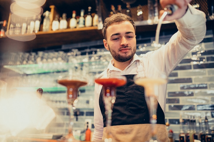 Foto gratuito barista bello che fa bere e cocktail ad un contatore